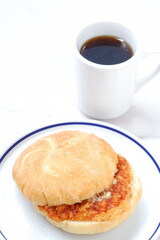 オーストリア発祥のロールパンのカイザーゼンメルにハムカツを挟んだサンドイッチとコーヒーの軽食をとる