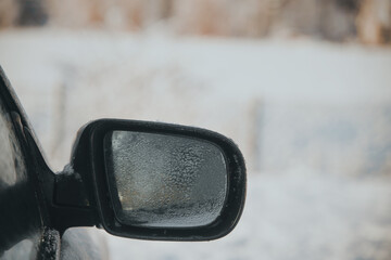 Side view mirror covered with raindrops. Powered car mirror.