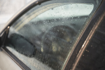 Wet car window. Vehicle glass covered with melted snow and water.