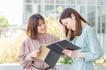 悔しい思いをして後悔するアジア人女性と慰める女性（友達・大学生・ビジネスウーマン）