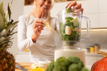 Beautiful woman preparing healthy smoothie in a kitchen 
