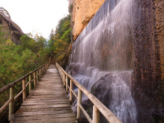 natural mountain landscape in Beteta, Cuenca, Spain, with a waterfall and a bridge next to it, in the background the forest