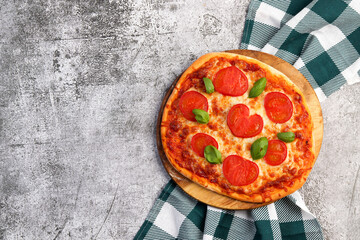 Homemade Pizza margherita with tomatoes, basil and cheese on a round wooden cutting board on a dark grey background. Top view, flat lay