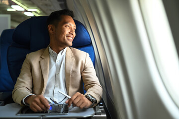 Satisfied businessman passenger sitting comfortable seat and looking out through window of the...