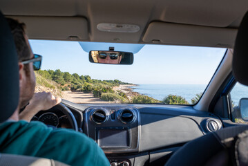 View of a blurred man driving a car on a dirt road through wild Mediterranean coast.