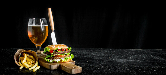 Burger with a knife,fries, beer in a glass.