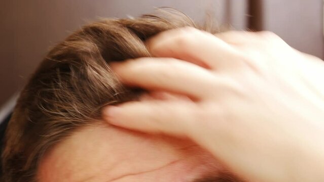 close-up of the male crown. a man combs his short hair. daily hygiene procedures. hair care and haircut.