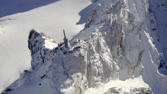 Observatory and antenna summit of Aiguille du Midi near Mont Blanc Mountain peak with visitor center below, Aerial dolly up looking down shot