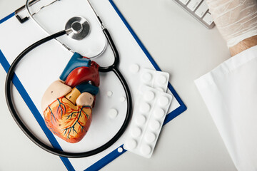 Stethoscope, clipboard and heart model on a doctor's desk