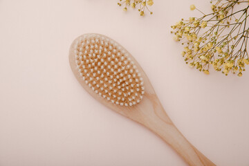 Wooden brush for dry anti-cellulite massage on pink background, top view. Skin and body care concept