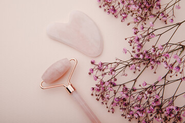 Self care and beauty theme. Face roller and gua sha massager with branch of gypsophila