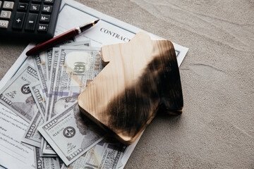 Top view of dollar bills, calculator and a burn house on an insurance contract. Fire insurance concept