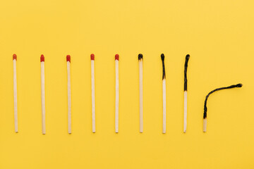 Evolution of matches from new to completely burnt on a yellow background as a symbol of aging or...