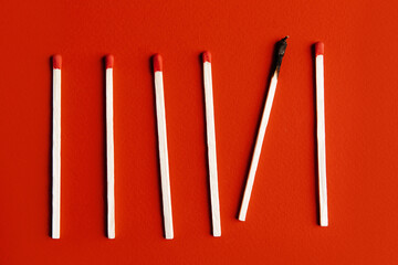 Matchsticks with one burned out on a red background