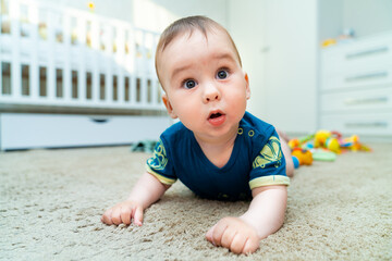 Baby boy with his first toys. Cute little boy lies on his stomach with emphasis on his hands.