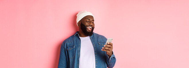 Technology and online shopping concept. Happy Black bearded man reading message and smiling, using...