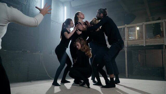Group of men and women standing up gesturing around leading actress as live camera zoom out. Confident talented Caucasian actors and actresses rehearsing modern play on backstage in theater