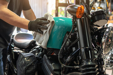 Biker man cleaning motorcycle , Polished and coating wax on fuel tank at garage. repair and...