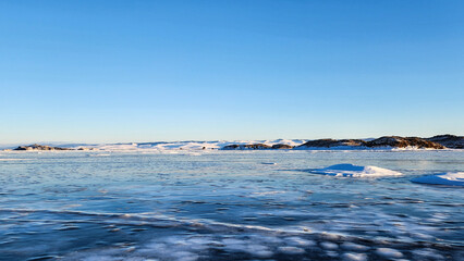 Winter sea sunset. Panoramic view of the snow-covered shore of the frozen sea, the lake at sunset. Shards of ice close-up. Christmas, seasons, winter. Selective focus.