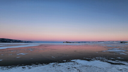 Winter sea sunset. Panoramic view of the snow-covered shore of the frozen sea, the lake at sunset. Shards of ice close-up. Christmas, seasons, winter.  Selective focus.