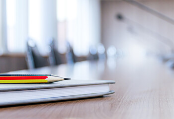 Pencil and notebook on table in meeting room