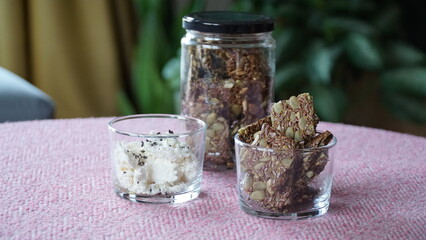 seed crackers in a jar and in a small bowl. curd cheese and black cumin on top in another small...