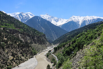 Naklejka premium A valley with green and snow capped mountains with a river