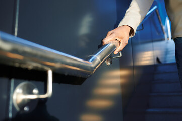 Close up of a black man's hand gripping the railing of some stairs. Handle and handrail concept.