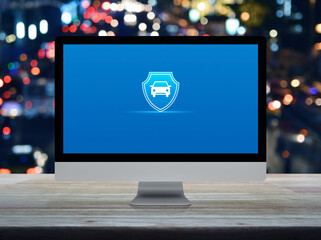 Car with shield flat icon on desktop modern computer monitor screen on wooden table over blur colorful night light traffic jam road in city, Business automobile insurance online concept