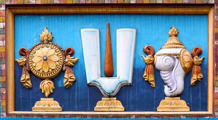 Chakra disc, Vaishnava Tilak and Shankha conch - symbols attributes of Vishnu Balaji on the wall of a Hindu temple in Tirupati, India. - obrazy, fototapety, plakaty
