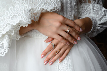 The bride's hands are detailed, they are laid on dress.