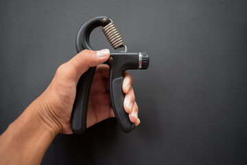 Hand exercising, squeezing a handgrip, man gripping hand exercise gripper.