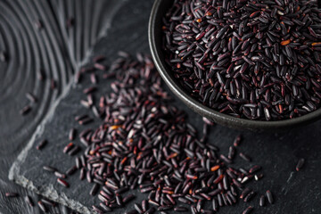 raw fresh black rice on black wooden rustic background