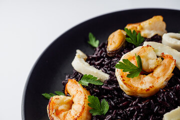 delicious black rice with shrimps and seafood on a white background