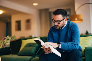 Adult male businessman reading a book at home. - obrazy, fototapety, plakaty