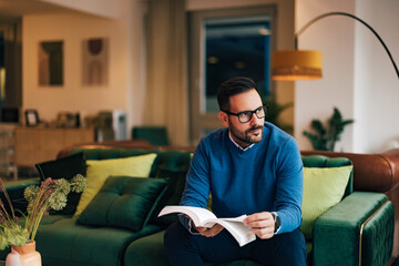Businessman holding a book and planning the day, sitting on a couch.