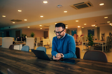 Smiling man employer having an online meeting over the laptop, sitting at the office.