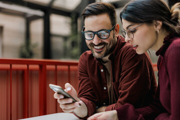 Smiling business people using a mobile phone, searching for something online.