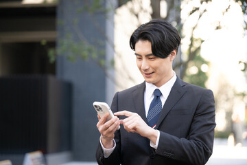 Asian businessman tapping his phone outside up