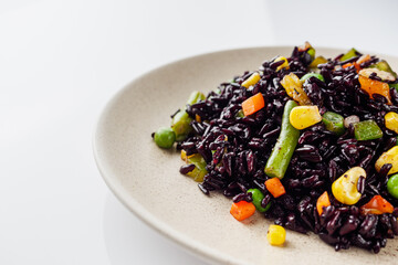 delicious black rice with vegetables on a white background