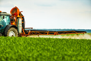 Scientific crop protection with tractor-applied herbicides, pesticides, and fungicides, farmer in...