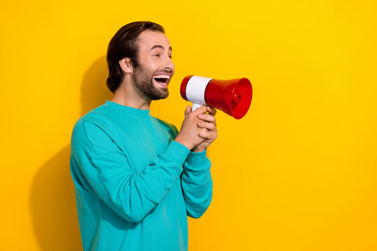 Photo of funny funky man wear turquoise clothes screaming toa empty space isolated yellow color background