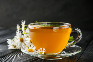 aromatic hot chamomile tea on a black rustic wooden background