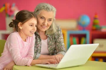 Fototapeta na wymiar portrait of happy grandmother and daughter using laptop