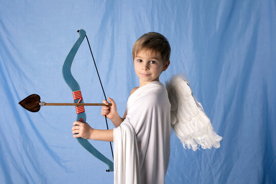 Little cupid toddle boy, holding bow and arrow, beautiful blond cherub