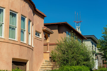 Row of house or home facades with visible windows and front yard trees with proch in front yard and blue sky background