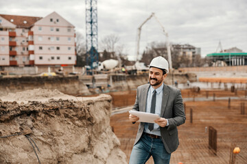 Fototapeta na wymiar A happy contractor is standing on construction site with paperwork.