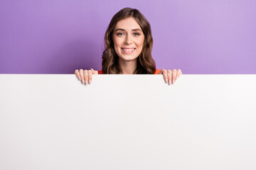 Photo of young promoter lady smiling hold huge paper white wall proposition new brand clothes sale shopping isolated on violet color background