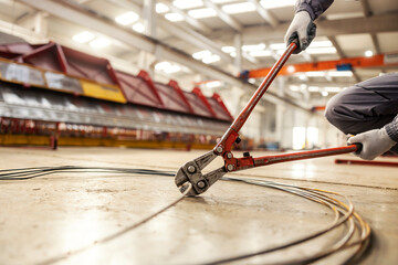 Close up of hands cutting wire with wire cutter in facility.