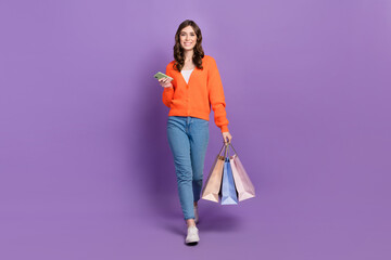 Full length photo of shiny sweet lady wear orange cardigan holding shoppers chatting device...